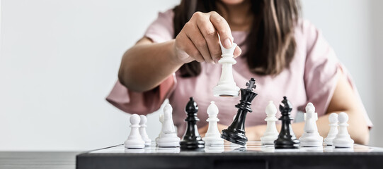 Close-up a businesswoman holding a white chess piece and colliding with black chess until she almost falls, business management and risk management concept, compared to playing a game of chessboard.