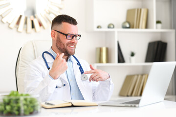 Positive professional male doctor in white coat giving professional medical consultation to patient online