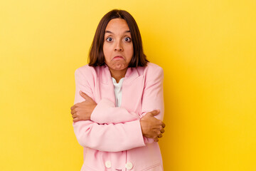 Young mixed race woman isolated on yellow background shrugs shoulders and open eyes confused.