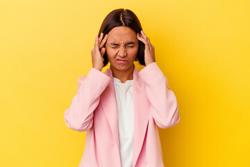 Young mixed race woman isolated on yellow background touching temples and having headache.