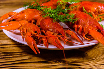 Plate with boiled crayfishes on wooden table