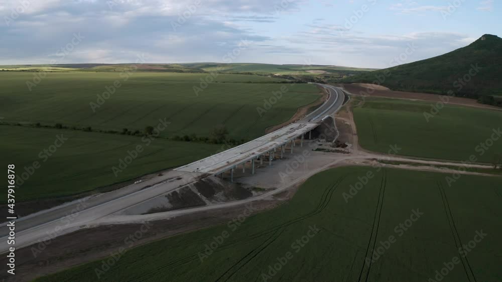 Wall mural drone flight over beautiful nature with green rolling fields and a newly built highway that passes t