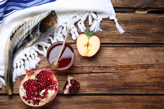 Honey, pomegranate, apples and shofar on wooden table, flat lay with space for text. Rosh Hashana holiday