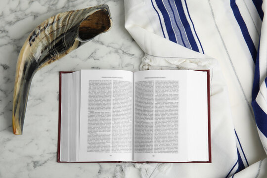 Tallit, shofar and open Torah on white marble table, flat lay. Rosh Hashanah celebration