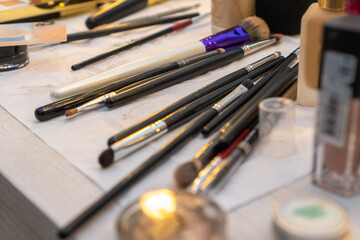 Many different brushes, makeup jars on the makeup artist's desk close-up, selective focus