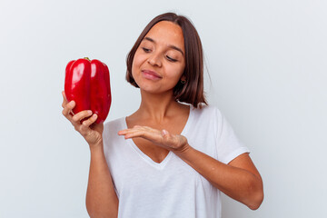 Young mixed race woman holding a pepper isolated on white background