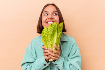 Young mixed race woman holding a lettuce isolated on beige background