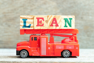 Fire ladder truck hold letter block in word lean on wood background