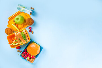 Back to school, Healthy tasty kid lunch box with sandwiches, nuts, fresh fruits and vegetable sticks. With school supplies, pencils, notebooks, on bright blue background flatlay top view copy space