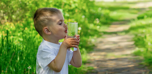 The child drinks clean water in summer. Selective focus.