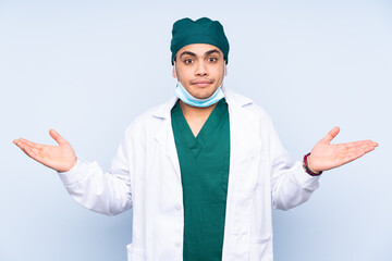 Surgeon man with uniform isolated on blue background having doubts with confuse face expression