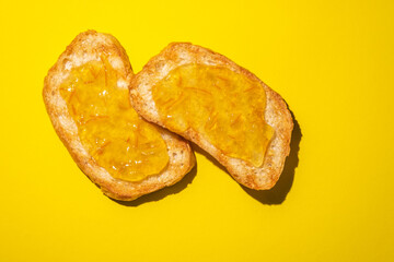 Toast with orange marmalade on a yellow background