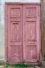 Fototapeta na wymiar An old dark pink wooden door on the stone wall.
