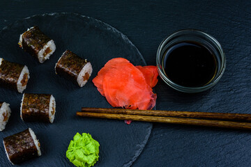 Sushi maki roll with tuna, wasabi and ginger on a slate board. Japanese food