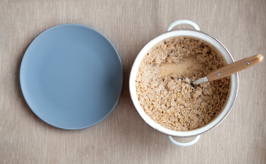 oatmeal in a saucepan with empty plate. Oatmeal breakfast in the morning