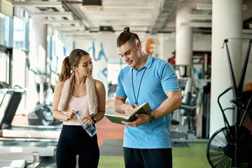 Athletic woman and her personal trainer making training plans in a gym.