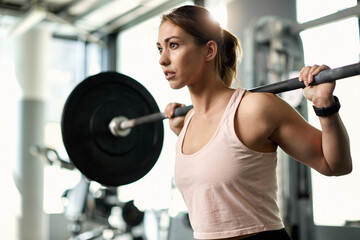 Determined female athlete having weight training in a gym. - obrazy, fototapety, plakaty