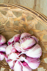 Top view of Purple Garlic bulbs in wicker basket on a wooden background