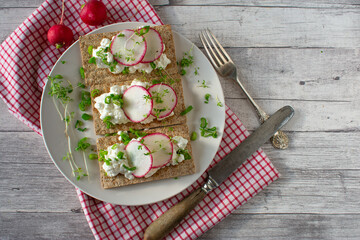 Crispbread with cottage cheese and sliced radish on a plate