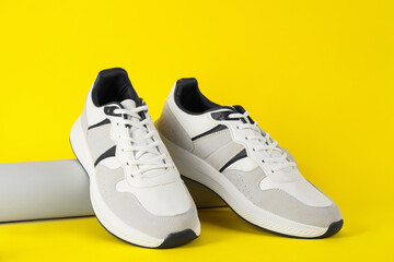 Pair of stylish sneakers on yellow background