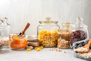 Different legumes in glass jars: chickpeas, pasta, beans, peas, lentils. Zero waste storage,...