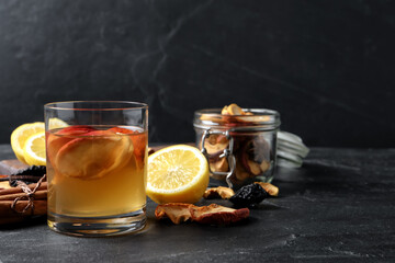 Delicious compote with dried apple slices and ingredients on black table, space for text