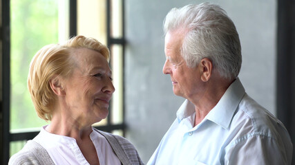 Romantic senior couple relaxing at home looking at each other and smiling