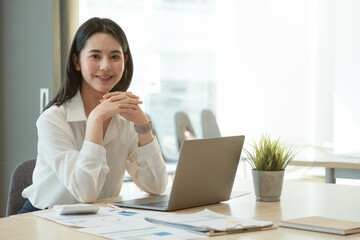 Portrait Of Attractive Asian Businesswoman Working On Laptop for marketing plan.