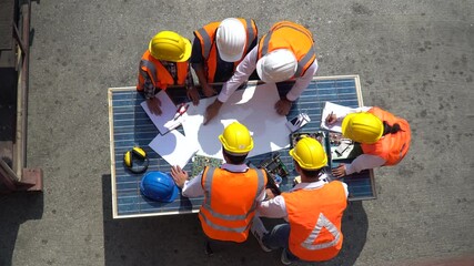 Group of Solar power plant Engineers Team Meeting and discussion to brainstorming with blueprint on solar cell top table Planning for a New Project of Environmental Power at construction site outdoors