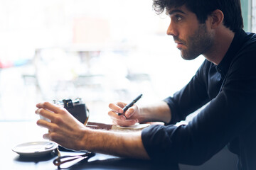 Adult handsome man sitting in cafe and interviewing anonymous person