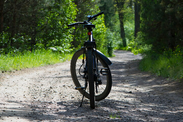 Fototapeta na wymiar rear wheel of a mountain bike. A mountain bike stands on a trail in a summer forest. cycling outdoor. concepts of renovation, sports, cycling, outdoor activities. spring park. close-up