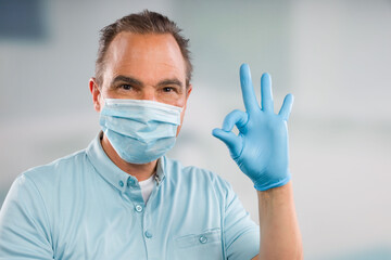 Doctor with medical face mask and medical gloves makes an everything okay gesture