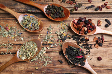 Flat lay composition with different teas and spoons on wooden table