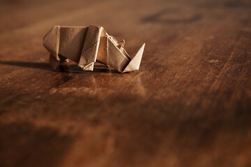 Paper origami rhino isolated on wooden background. Handmade rhinoceros.