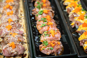 Row of wagyu beef sushi on the long plate, served at the premium Japanese food restaurant. Close-up and partail focus on once piece of the sushi.