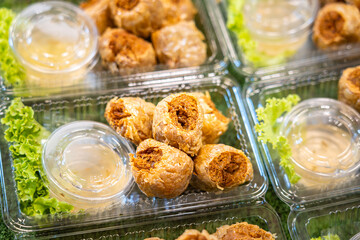 A set of deep fried crab meat dumpling with sweet sauce and vegetable which is sale in the plastic box. Chinese style food object photo.