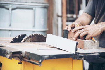 Carpenter man is working with circular saw machine table tool for cutting his wooden piece work