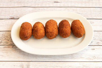 Homemade Iberian ham croquettes on a white tray prepared