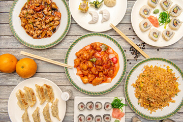 Aerial image of typical Chinese food dishes with some Japanese sushi and a garnish of seaweed and ginger