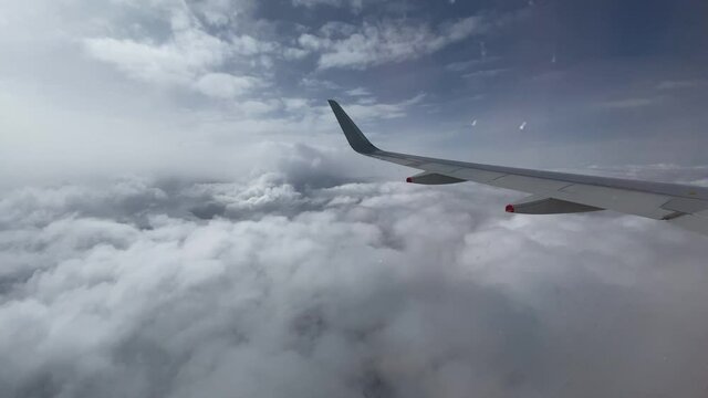 View out of aircraft window as it flies above the clouds.