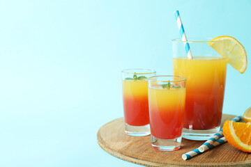 Board with Tequila sunrise cocktail on blue background