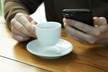 Man drink coffee and holds phone, close up
