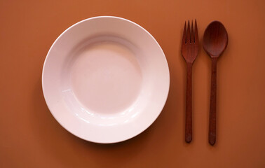 Empty plate with spoon and fork on wood background.