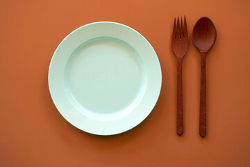 Empty plate with spoon and fork on wood background.