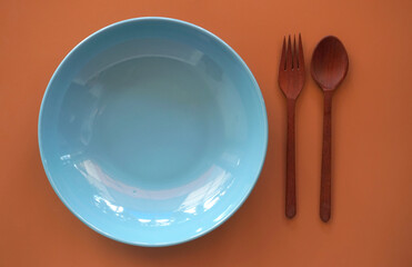 blue plate with spoon and fork on wood background.