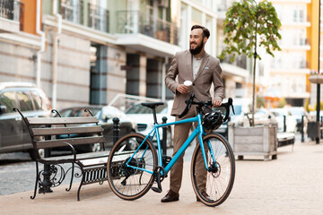 Urban environmentally friendly transport. A bearded man in a business suit rides a bicycle to work in the morning. - obrazy, fototapety, plakaty