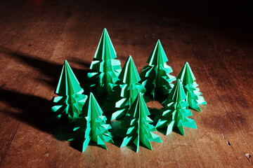 Origami trees isolated on dark background with long shadow.