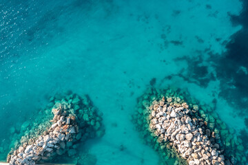 Greece, Cyclades. Aerial drone view of a stone breakwater on turquoise color sea water