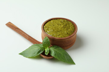 Bowl of Pesto sauce, basil and spoon on white background