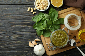 Pesto sauce and ingredients for cooking on wooden background